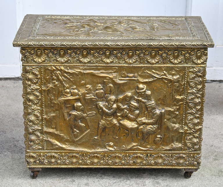 A late 19th century 'Black Forest' embossed brass depiction of a bucolic celebration;  a motif dating back to the Renaissance period.  The size of a small coffer or trunk, it serves perfectly for fireside kindling storage.  It may alternatively be