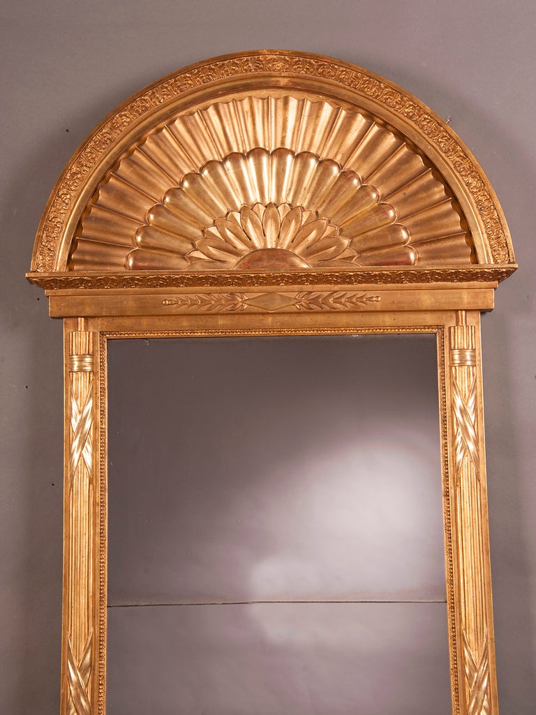 An exceptional Scandinavian hand carved and gold leaf Neoclassical frame enclosing the original two mirror glasses from Sweden c. 1810. The absolute symmetry of the form of this frame with its fan shaped crown to the horizontal placed pair of leafy