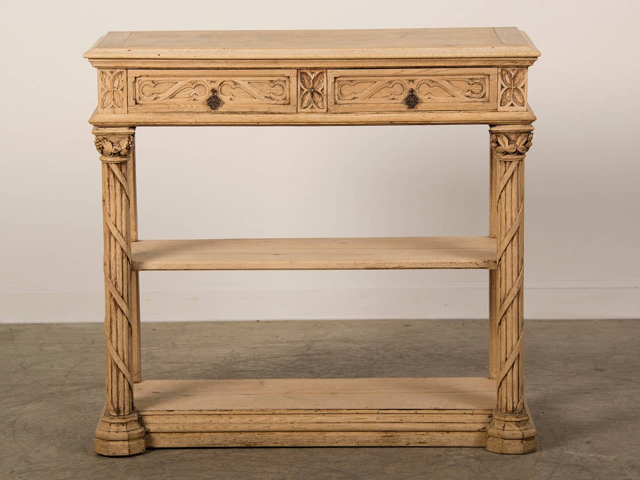 A Renaissance style carved oak desserte from France c. 1880 having a pale colouration. Please notice the striking combination of the carved columns on the left and right each entwined with a ribbon and capped with a carved capital of fruit and