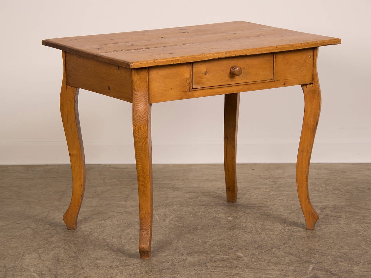 A large Louis XV style antique French pine table from France circa 1875. This table has a rectangular board top supported by four robust legs each having a simple cabriole profile. Unusually each of the four legs is set at a fourty five degree angle