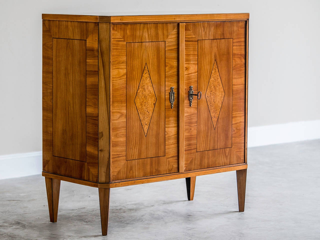 Biedermeier period cherrywood inlaid buffet or cabinet, Vienna, Austria, circa 1820. This two door cabinet possesses a powerful visual impact despite its diminutive scale. The balanced and symmetrical arrangement of the design takes advantage of the