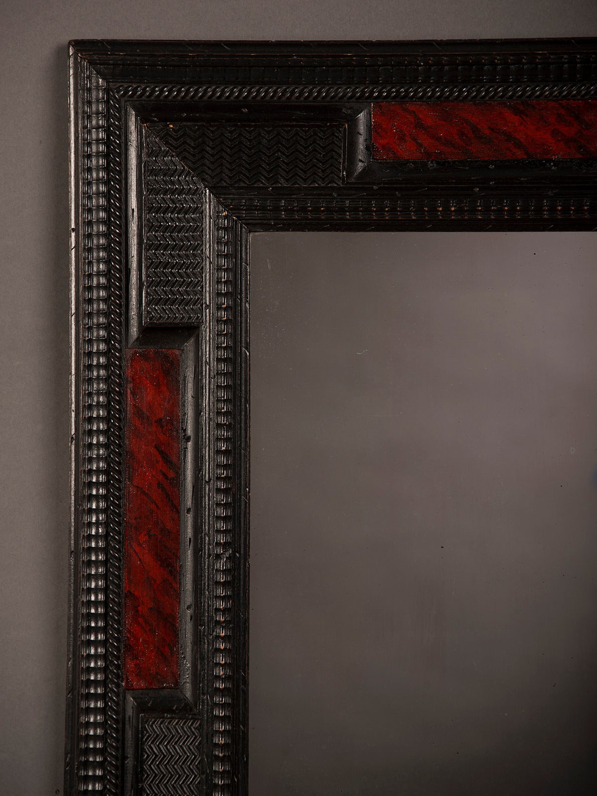 A terrific Dutch style frame from Holland circa 1860 featuring the distinctive mix of carved and ebonized wood offset with four panels of faux painted tortoise shell surrounding the antique mirror glass. Please notice the unusual three-dimensional