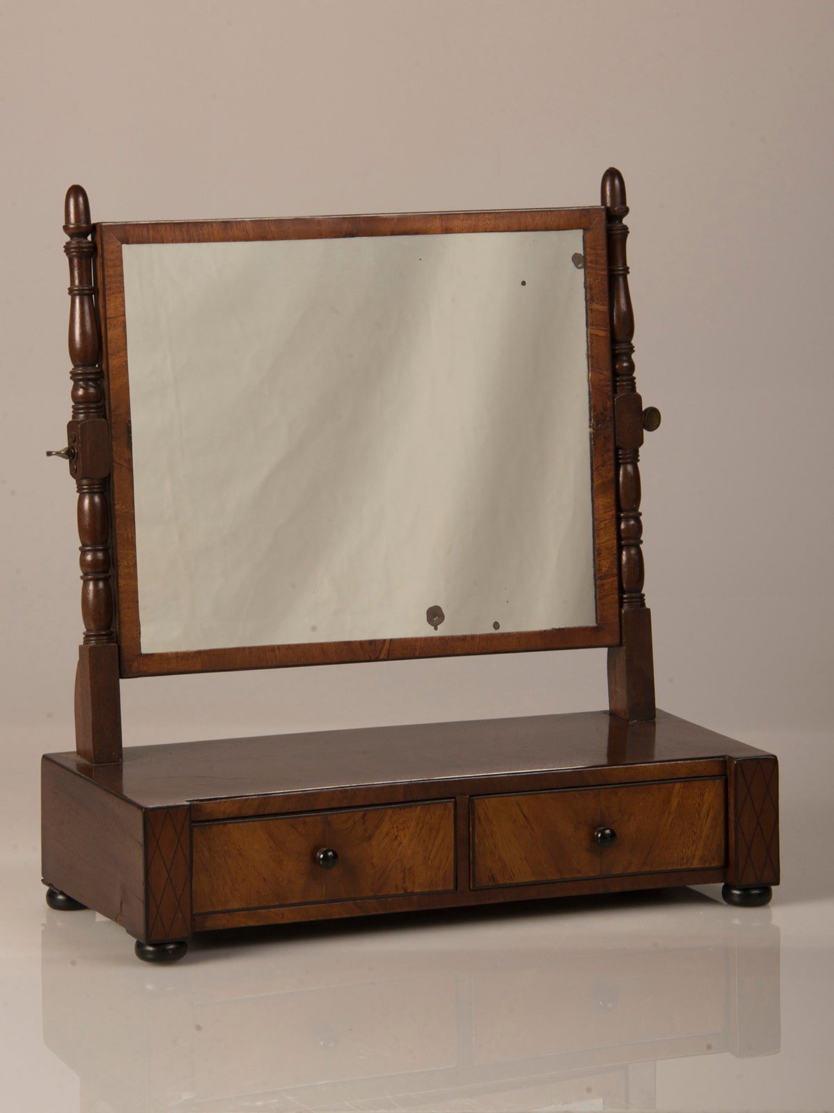 A William IV period mahogany dressing mirror with turned columns, having two drawers and standing on bun feet from England circa 1830.