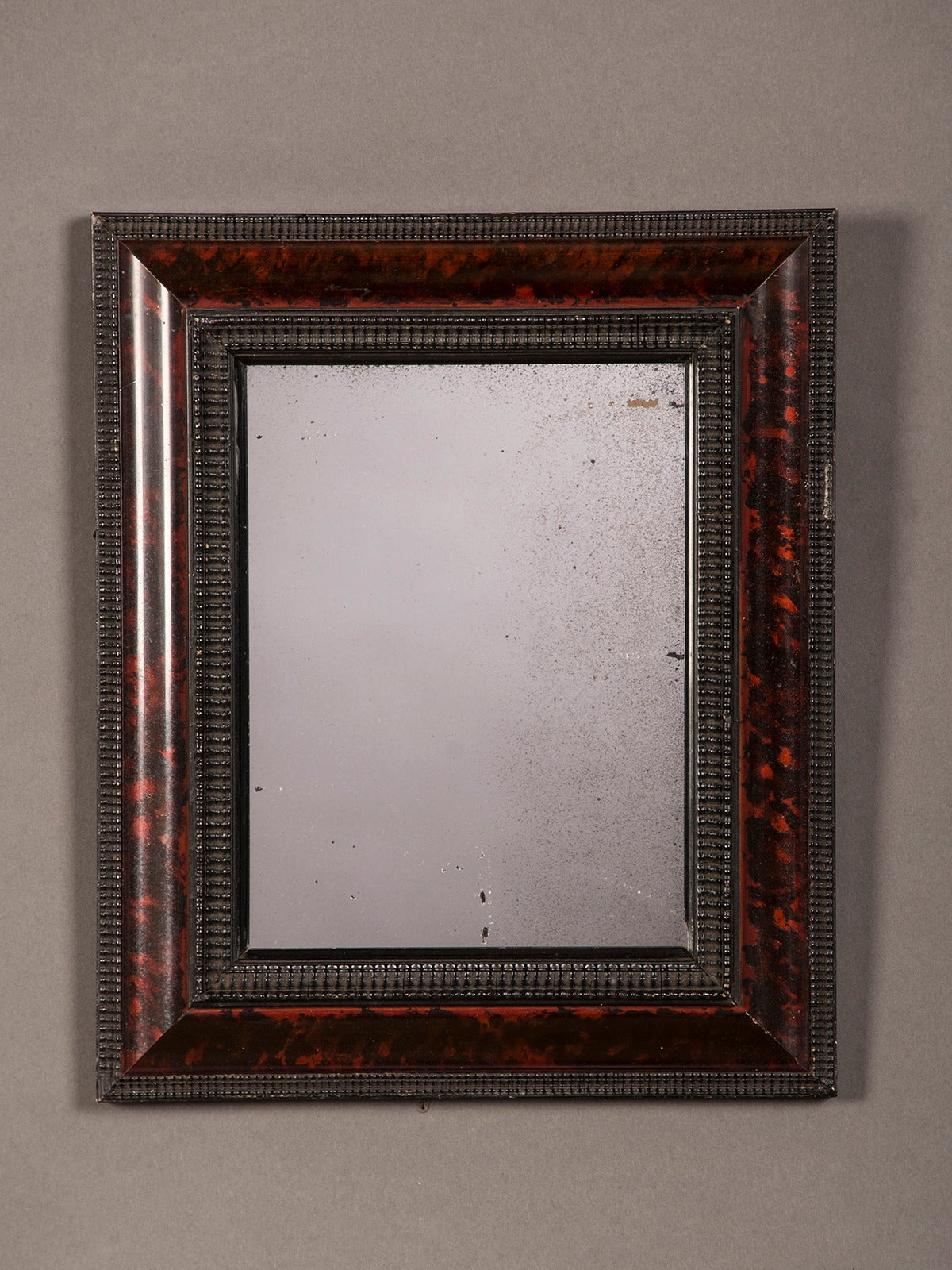 A Dutch style frame of ebonized timber enclosing a beautiful border of hand-painted faux tortoise shell from Holland circa 1865 surrounding the original mercury glass mirror. The diminutive size of this mirror harkens back to the days of the 16th
