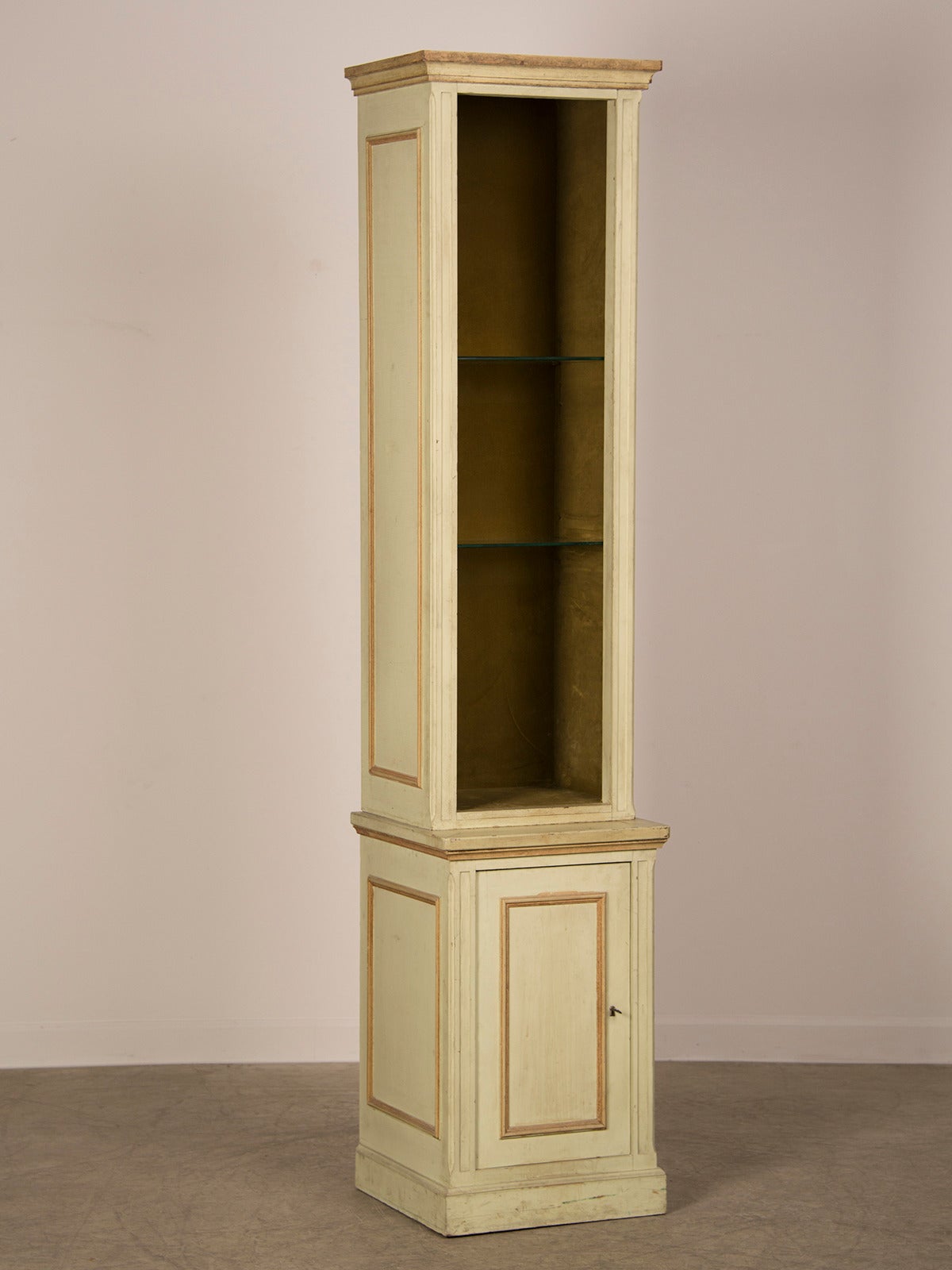 A tall and slender Georgian style cabinet with moulded detail and the original painted finish from England c. 1920 with an open display upper section and a cabinet below. The detailing and colour is reminiscent of the drawing room at Highclere