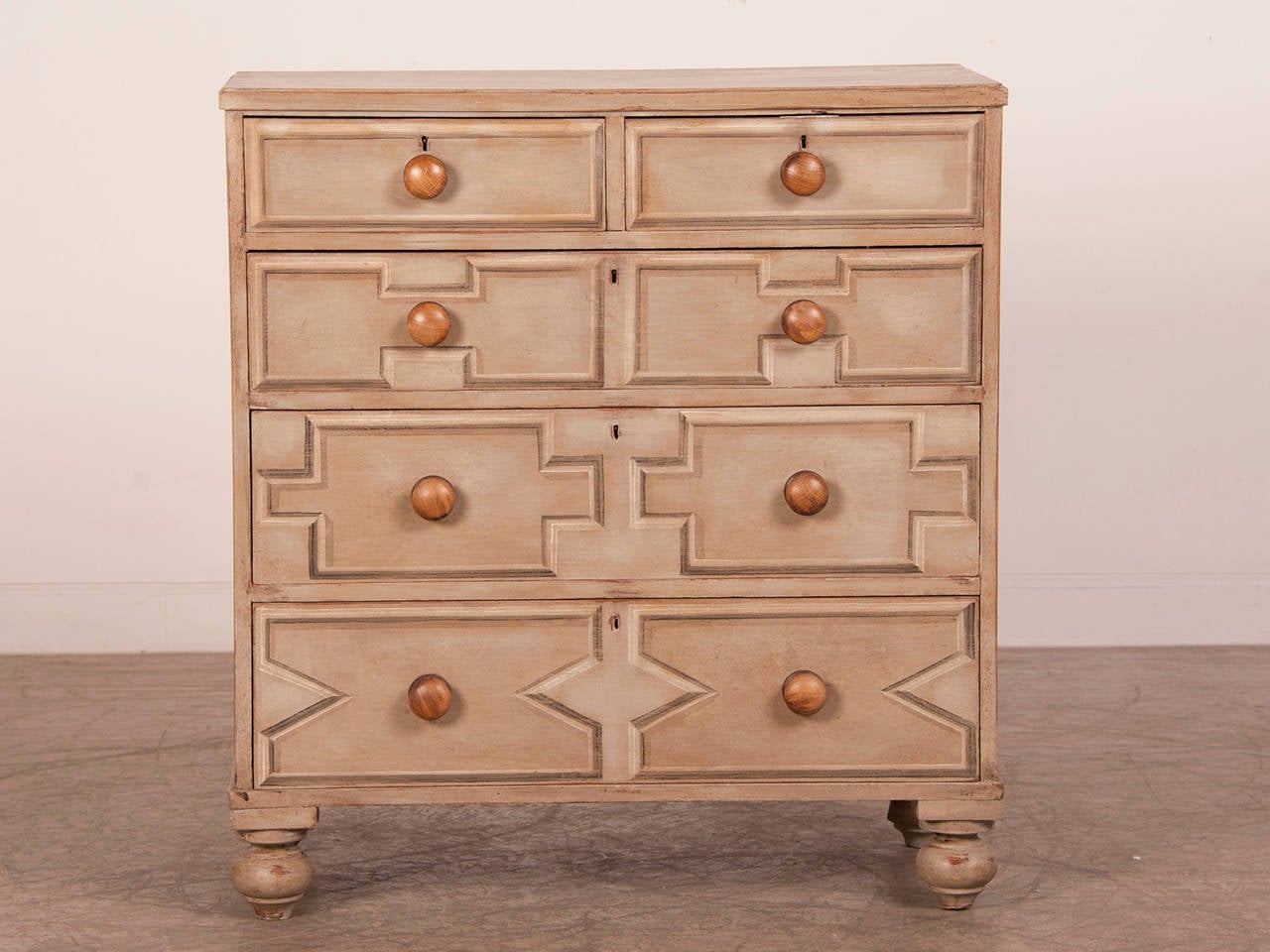 A large pine chest with five drawers from England c.1865 standing on the original turned feet now decorated with a custom painted finish with a geometric pattern reminiscent of the Jacobean period. The painter's use of shaded colours to create a