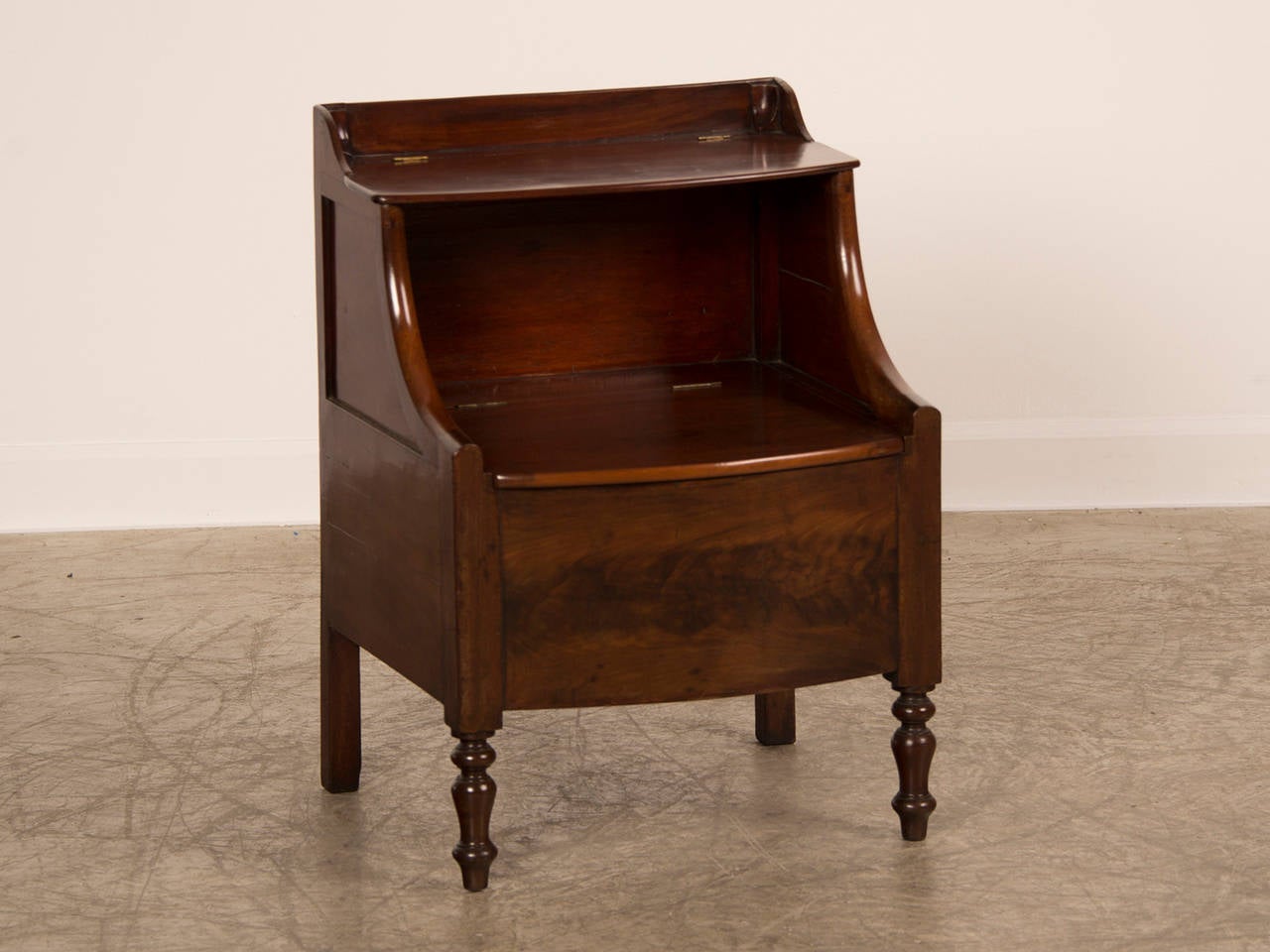 A William IV period mahogany side cupboard with two lift lids having a bow front and turned front legs from England c. 1840.
