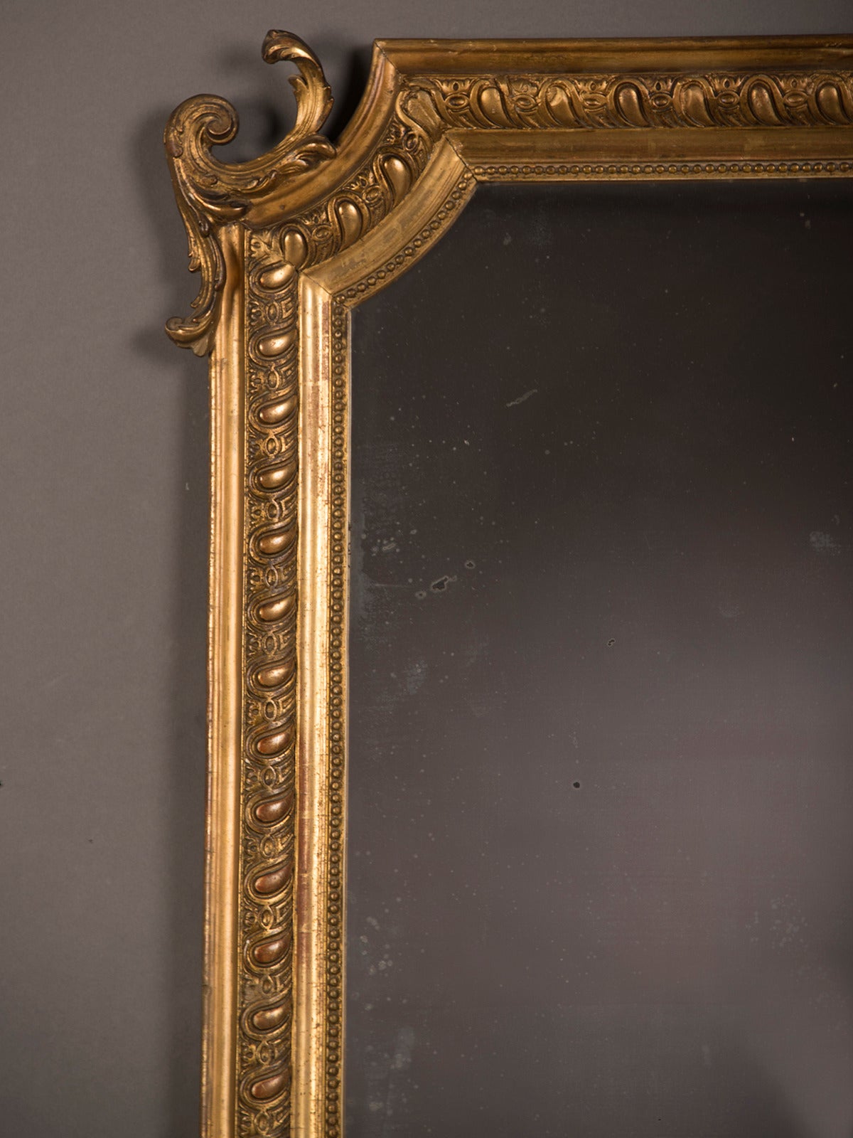 A handsome Louis Philippe style gold leaf framed mirror from France circa 1875 enclosing the antique mirror glass plate. Please notice the attractive symmetry of the decorative pattern evident in this frame. The teardrop shapes are smooth in