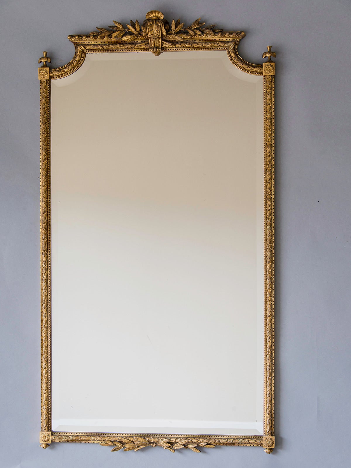 Louis XVI Style Gold Leaf Mirror, Belle Époque France c.1895. This grand and imposing mirror is notable for the slender and elegant proportion of its frame. The cartouche at the centre of the top has its origins in the designs of the Régence