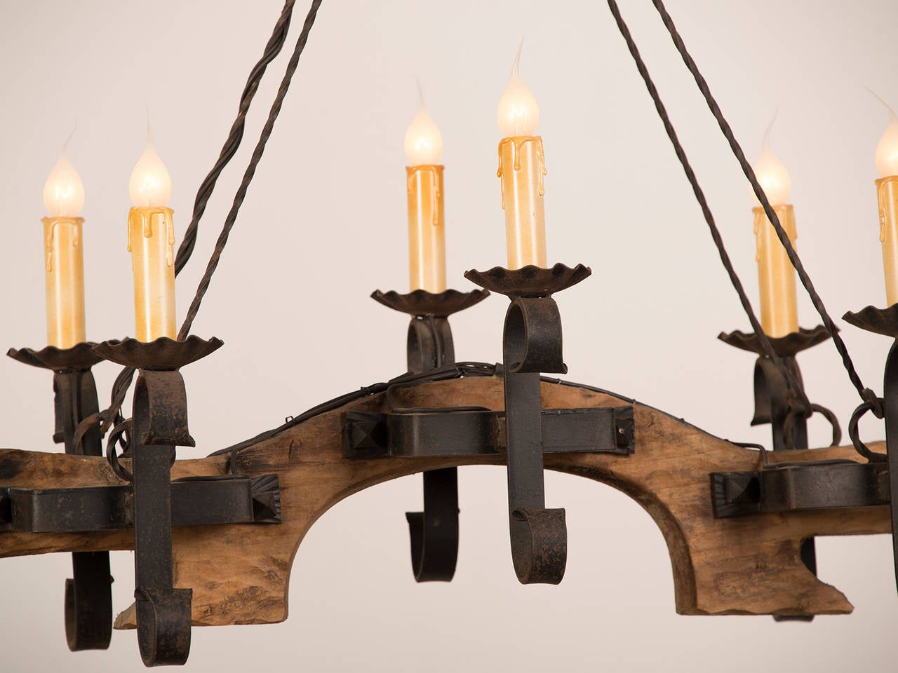 A charming fixture from a farmhouse in the Carmargue region of France c. 1920 having a carved wooden single ox yoke affixed with six iron brackets supporting the candle arms. This chandelier is suspended from four twisted iron rods connected to a