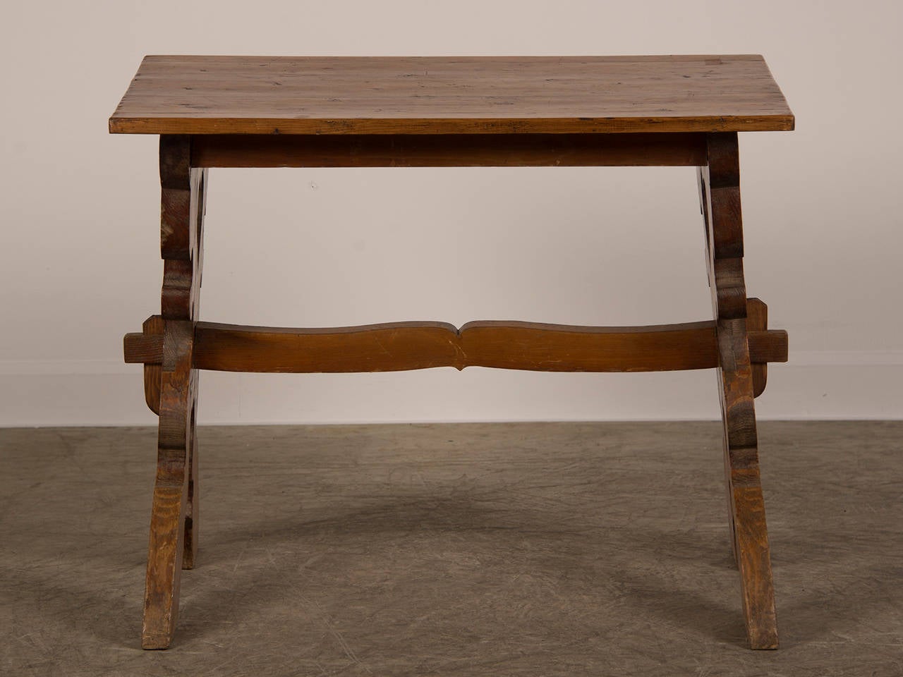 An unusual pine trestle table from Austria c. 1880 having legs in an elaborate X-form painted with a fanciful floral decoration joined by a shaped stretcher. The rectangular pine top is original. When you look closely at the base of the legs it is