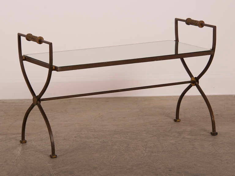 An Art Moderne iron coffee table enclosing the original mirror top with raised brass rope handles from France c. 1940. Please look at the close up photographs to see the handsome gilded details of the rope twist handles and circular medallions where