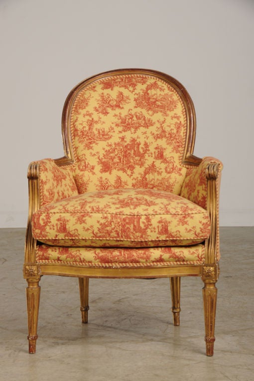 A charming Louis XVI style bergere from France c. 1890 with its original gold leaf finish. The shape of this chair is particularly pleasing with its oval back that is joined to curved sides with arms that have a scrolled profile. The front of the