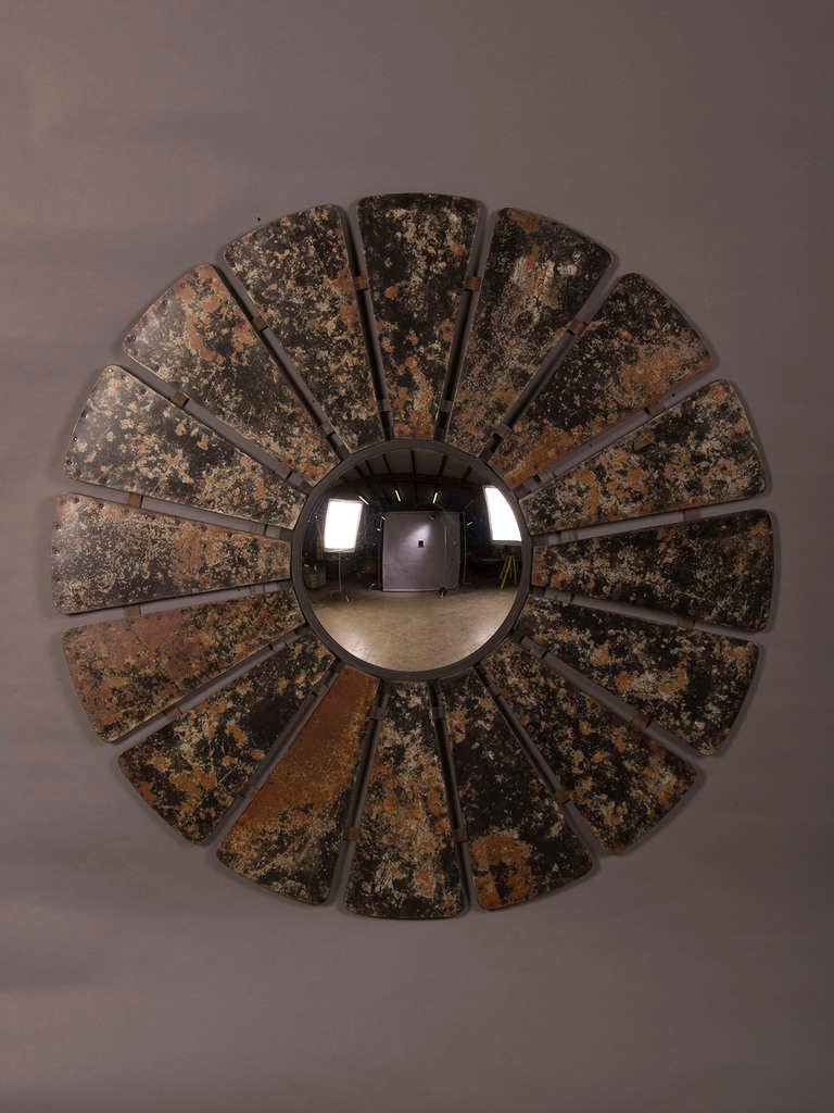 An enormous frame with sixteen petals of patinated zinc surrounding a circular convex mirror glass found in France with immense decorative impact. This unique mirror combines the graphic power of repetitive shapes with the variegated finish to the