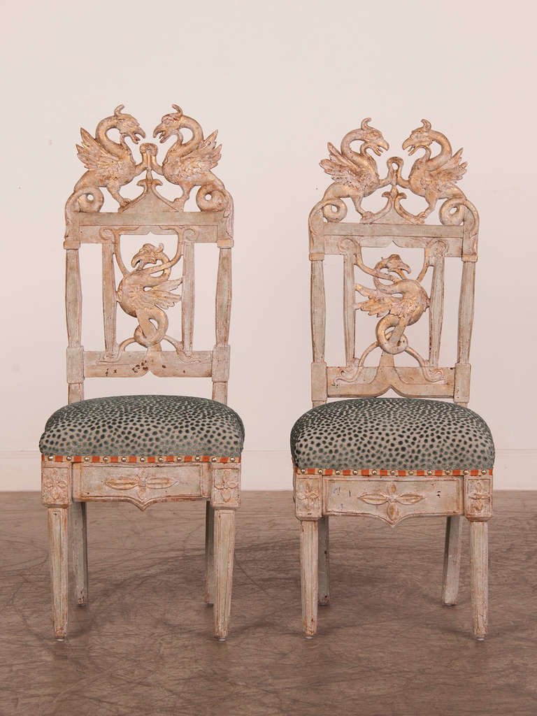 A pair of tall side chairs with gryphon carving from Italy c. 1790 with a gorgeous painted finish that have been custom upholstered.