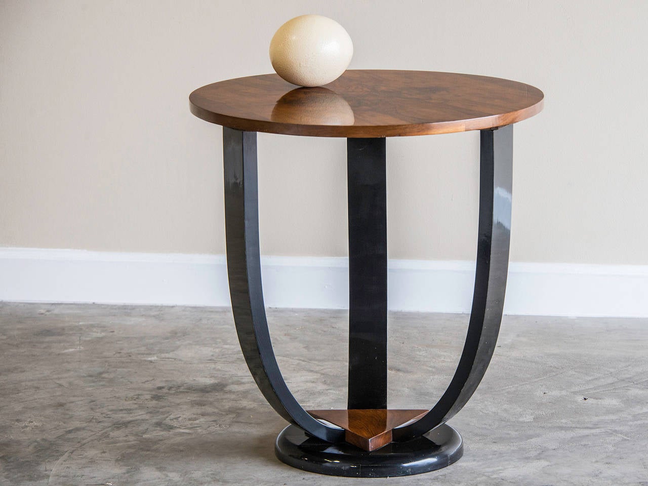 Art Deco period burl walnut and ebonized timber circular table from France, circa 1930. The powerful visual impact of the bookmatched walnut on the top surface of this table is matched by the sweep of the three ebonized legs. At the base of the