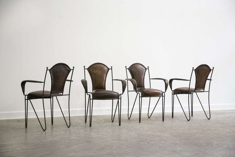 The four armchairs that comprise this set each possess a unique sculptural appearance. Each chair has an iron frame that is quite spare in its appearance. The seat back and seat itself have a slanted shape and retain the original leather material