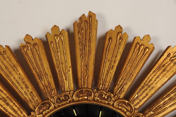 An exciting sunburst form gilded wood frame surrounding a circular convex mirror glass from France c. 1950. Please notice that the mirror glass has a border consisting of series of 