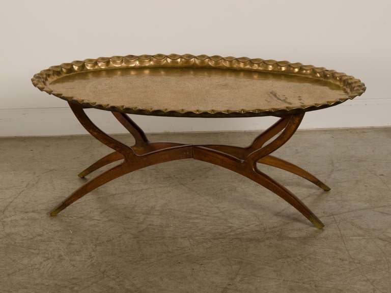 A grand scale solid brass oval tray from Persia c.1890 with its original folding wood base from Denmark c.1940. This remarkable tray possesses an extremely well formed crimped edge that boldly frames the interior. This repetition of the edge is