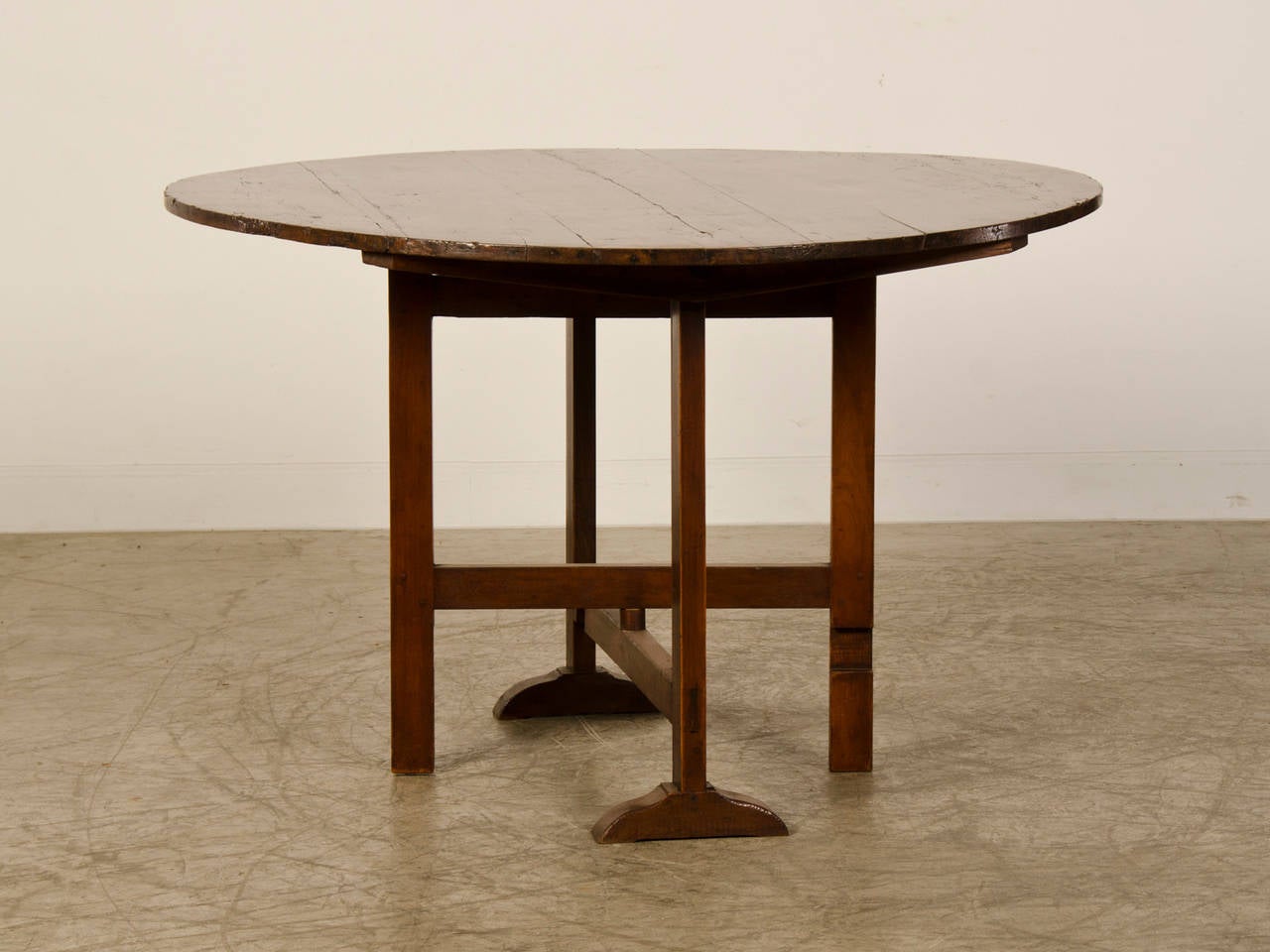 A handsome dark cherrywood wine table from France c. 1860 having a fully functioning tilt-top with a working leg mechanism that moves 90 degrees to support the table top with four sturdy legs. The planks on the round top are connected with