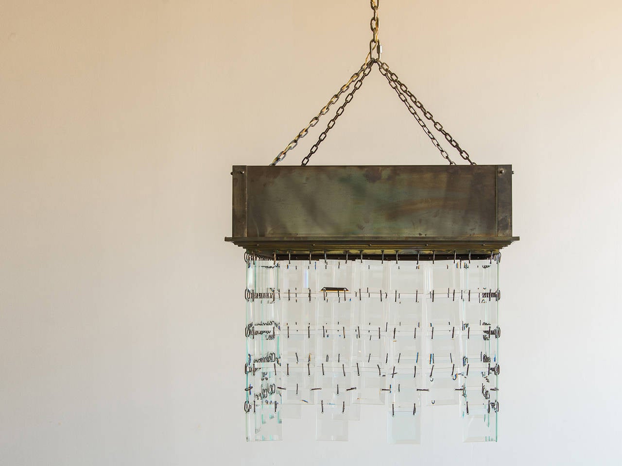 The square brass frame of this vintage Italian brass chandelier is unique in both material and shape and includes a series of square cut glass panels that form a curtain on each of the four sides. Because of the scale of the fixture it is definitely