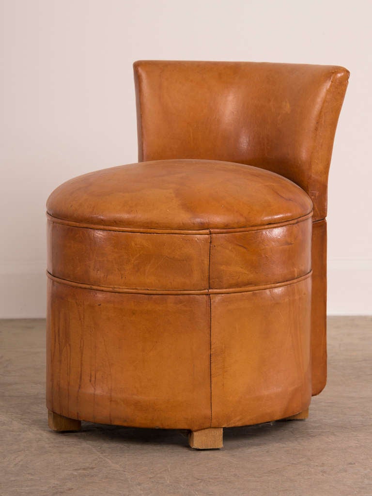 Art Deco period round leather chair with a low back from France c. 1930. This unusual chair is entirely circular in shape and is elevated on four low wooden legs recessed beneath the seat. The chair was originally used in a dressing room before a