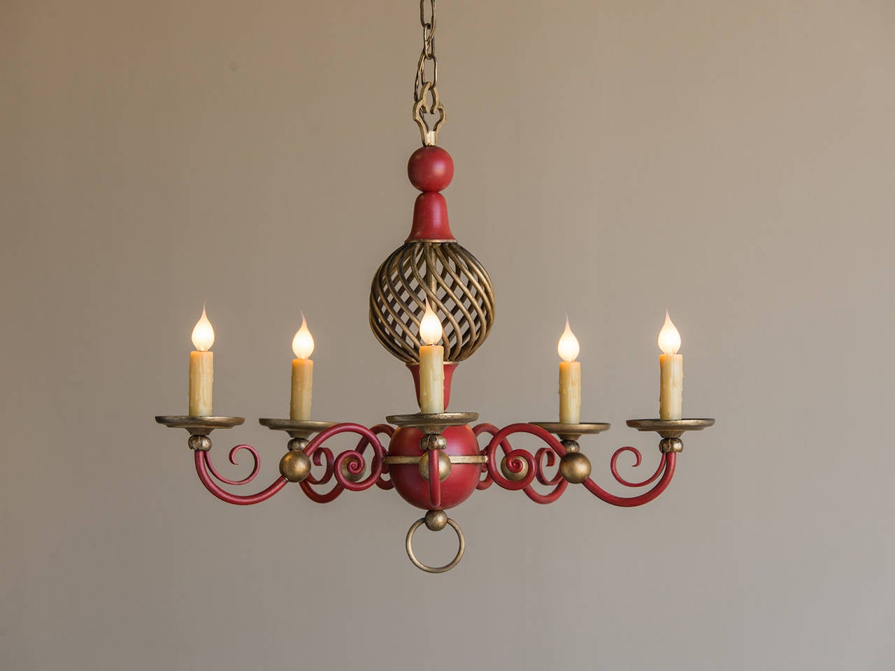 An intriguing vintage painted tole chandelier from France, circa 1940 having an open spiral twist above a closed sphere with five curved arms supporting the lights. The combination of the red and gold on this vintage French fixture makes a potent