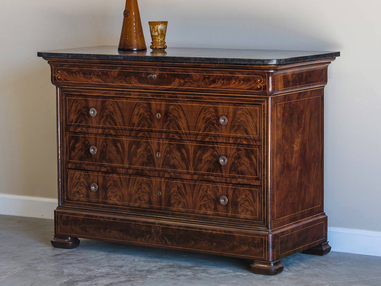 Louis Philippe mahogany chest of drawers, beech inlay, marble top, France, circa 1840. The extraordinary grain of the mahogany on this chest has been carefully matched to create the pattern of an upward Cascade with an enchanting variation in the