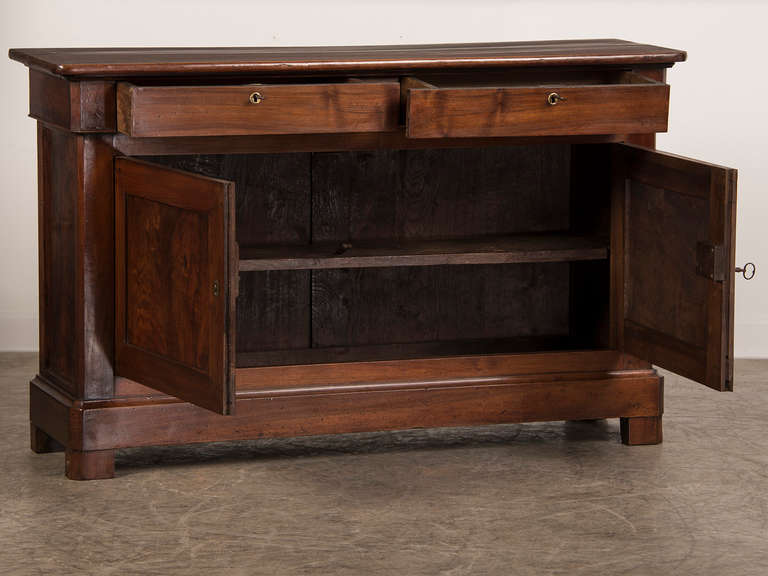 This Louis Philippe period walnut buffet features a pair of drawers above a pair of cabinet doors with the characteristic curved profile seen at the front corners that is a defining element of this style. In this particular buffet the unusual width