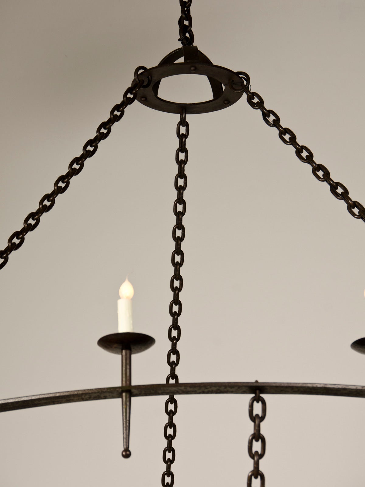 A striking two tier iron chandelier from France c.1920. The elegant and modern design of this enormous antique French iron chandelier from the early twentieth century is truly remarkable. The upper circular disk of solid iron is suspended from three