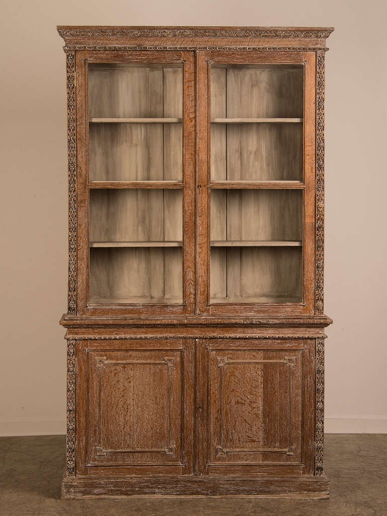 Cerused oak glazed bookcase from Warwick Castle, England c.1885. This handsome oak bookcase with its deeply carved details on both the upper and lower cabinet sections was made at the end of the nineteenth century for one of the dependant buildings
