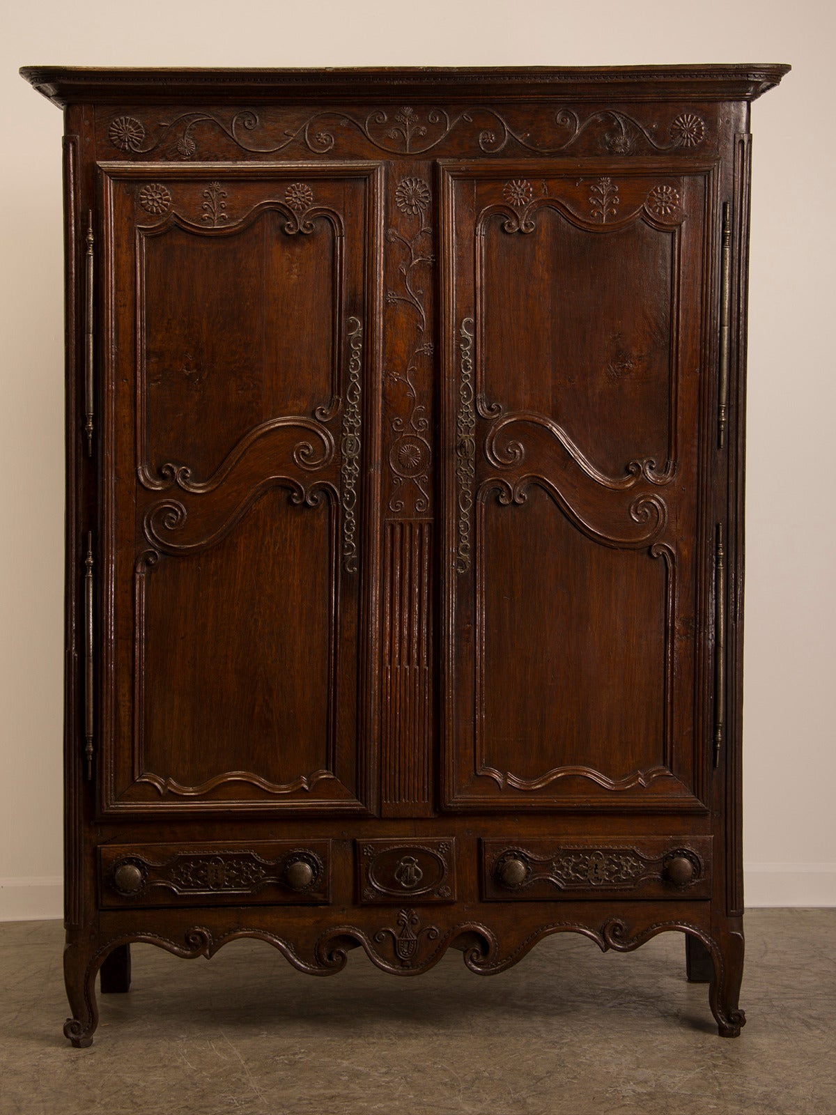 This hand carved antique French armoire showcases the superb cabinet making skills used during the eighteenth century. The overall symmetry and balance of the scrolls and flourishes delight the eye as it moves across the surface. The depth of the
