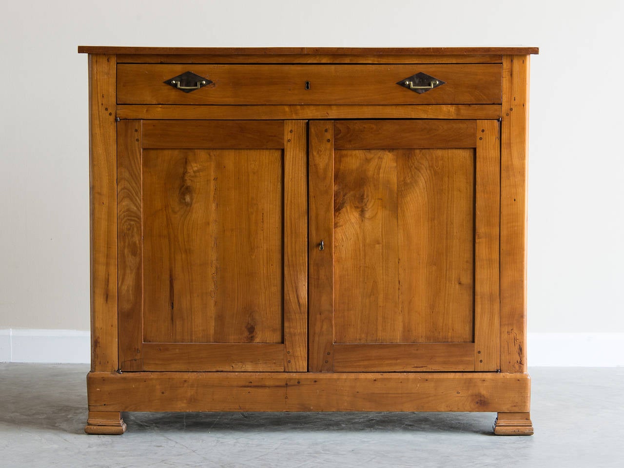 The tall and slender profile of this cherrywood antique French buffet accentuates its elegant appearance. Dating from the Louis Philippe period (1830-1848) the buffet embodies current desire for simplicity and style. The cherrywood timber has an