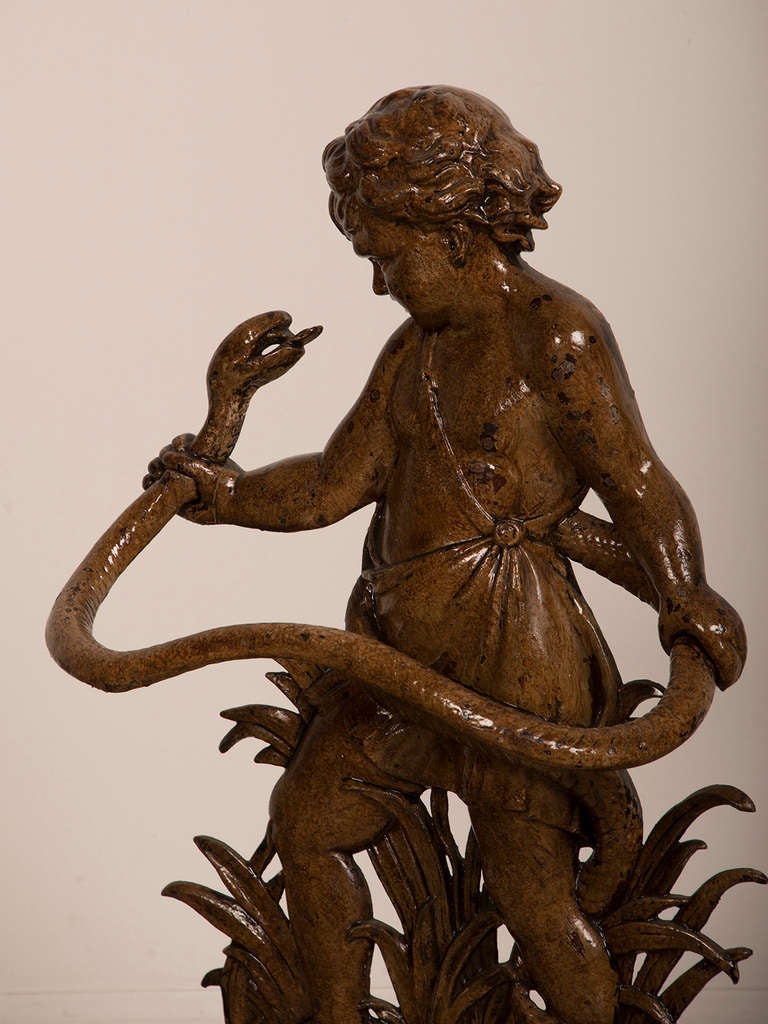 Painted Figurative Cast Iron Cane/Stick Stand , England c. 1880. This unique depiction of a shepherd child holding a loft a serpent while standing among river reeds is enhanced with a striking painted finish. The entire piece is made of cast iron