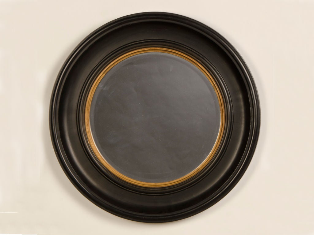 An Edwardian period round black frame enclosing the original beveled mirror from England c.1910. This dramatic mirror and frame refer back to the mirrors seen during the Regency period in England (1810-1830). The round shape of the frame is always