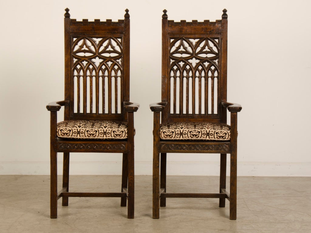A pair of oak armchairs in the Gothic Revival style from France circa 1880. These tall armchairs embody the essence of the Gothic as each chair has a long lean line that accentuates the vertical nature. The Gothic is an architectural style first