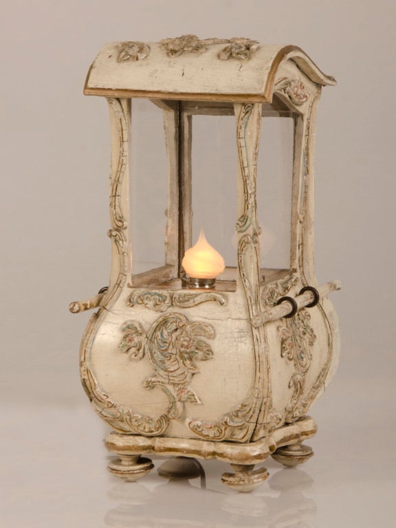A Louis XV style painted and carved wood sedan chair from France c.1830 now mounted as a table top lamp from France c.1920. This utterly charming lamp was originally used as a candle stand and retains the original antique glass panes placed in the