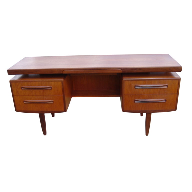 A vanity or desk designed by Ib Kofod-Larsen for G Plan from the 1960’s.  Teak with walnut trim.  A floating top over five drawers with sculptural molded wooden handles. The back of the vanity/desk is not finished