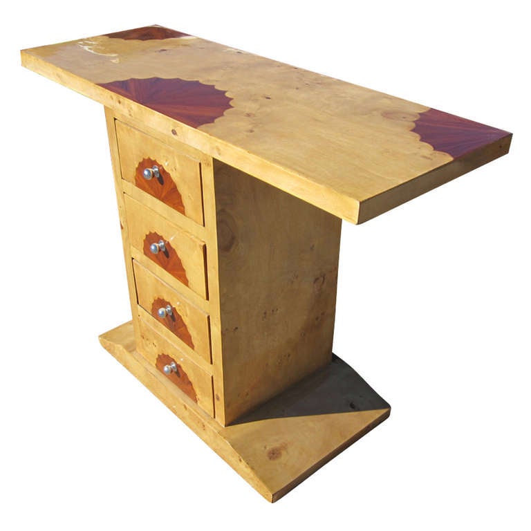 Art Deco table features a maple and burl top. The base is a tapered, rectangular form with three drawers accented with round, metal, drawer pulls. The top and drawers have distinctive scalloped wood inlays.