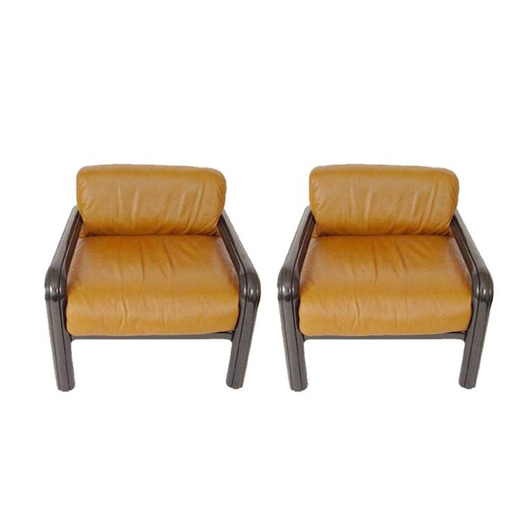 A pair of mid century modern lounge chairs designed by Gae Aulenti and made by Knoll.  Black enameled steel frames with caramel brown leather cushions.