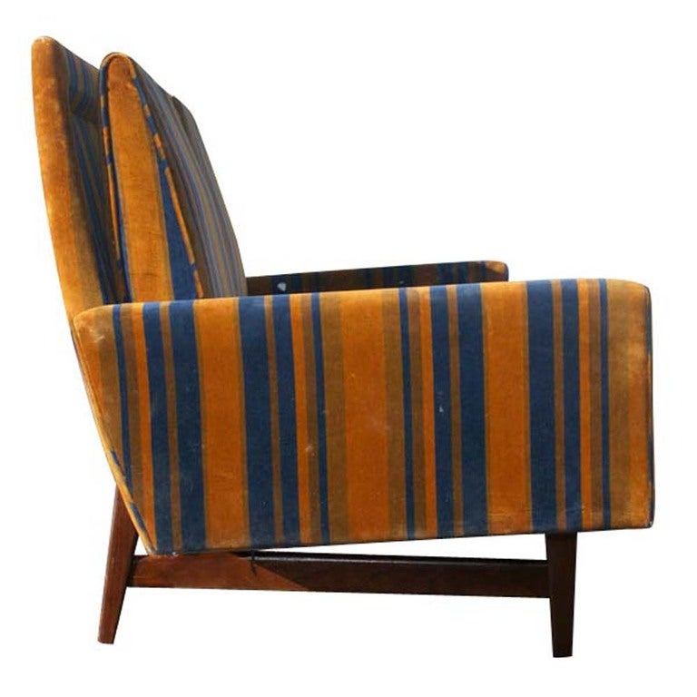 A mid century modern sofa designed and made by Jens Risom.  Original blue and orange striped upholstery with a walnut base.