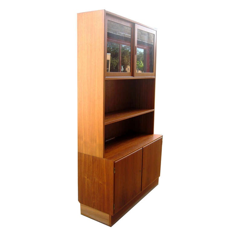 Gorgeous two-piece, Danish Modern cabinet by Poul Hundevad. All wood construction.

The top features glass enclosed adjustable shelving.

The lower cabinet doors open to reveal adjustable shelves lined with felt for flatware storage. 

Lower
