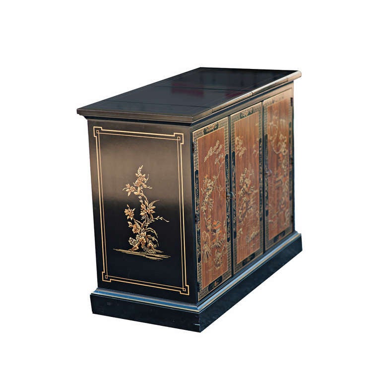 A stunning Chinese-style cabinet in black lacquer with lovely Chinoiserie decoration on front and sides. The top lifts up to become a buffet. Inside, one pull out drawer for flatware and shelves.