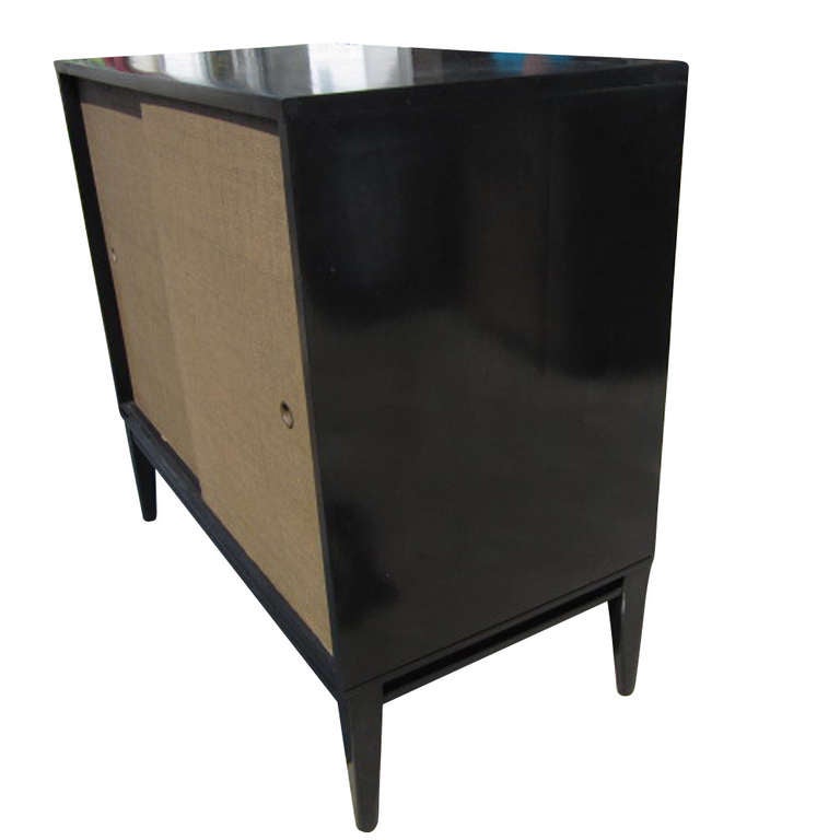 Circa 1950s cabinet designed by Paul Mcobb with signature grasscloth sliding doors and original black ebonized birch wood.