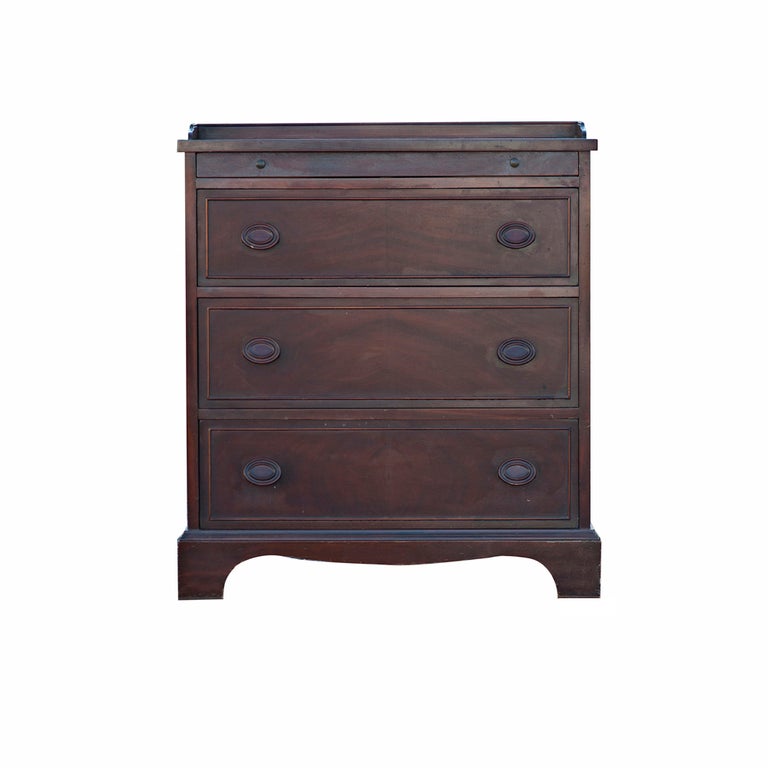 A small chest or dresser in solid mahogany in the manner of Duncan Phyfe.  Three drawers with wooden pulls, and a pull-out tray.  