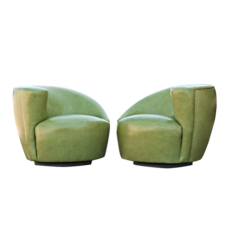 A pair of mid century modern swivel Nautilus lounge chairs designed by Vladimir Kagan. The pair include one left and one right facing chair on a swivel base with very elegant curves.  They are newly upholstered in elegant green patent leather.