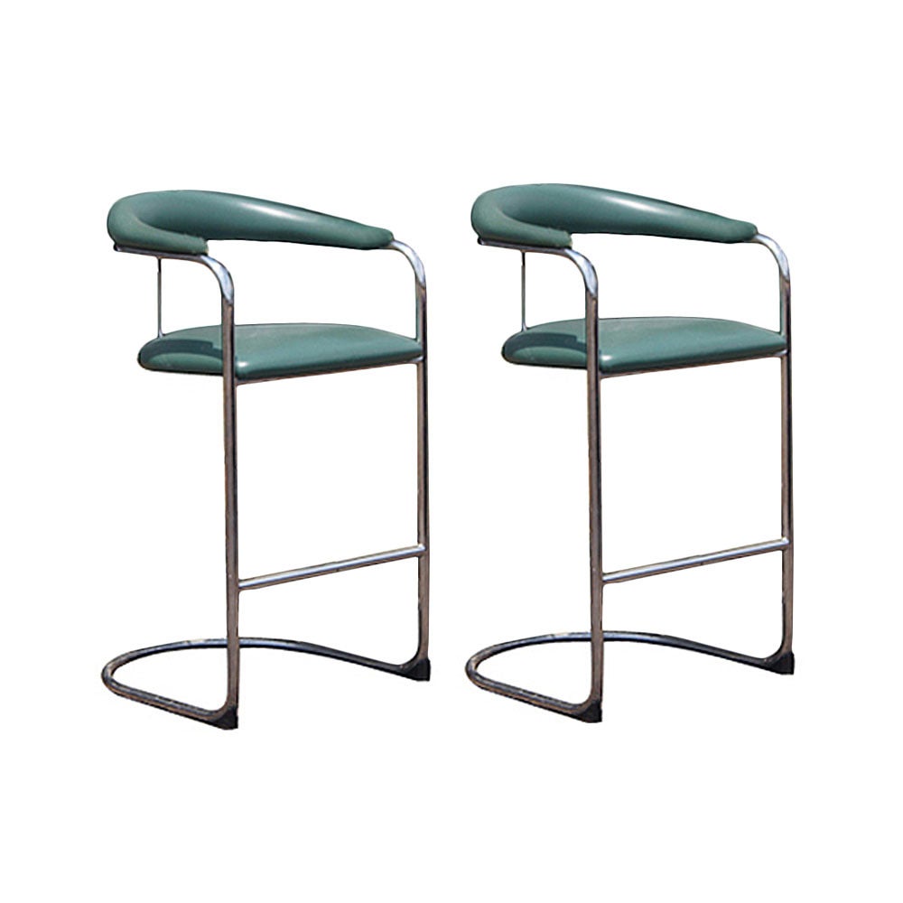 A pair of mid century modern barstools designed by Anton Lorenz and made by Thonet.  Tubular chrome frames with green vinyl upholstery.