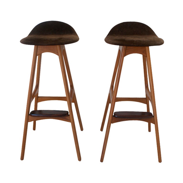 A pair of mid century modern barstools designed by Erik Buch and made by Oddense Maskinsnedkeri A-S.  Teak frame with a rosewood foot rest and brown suede upholstery.