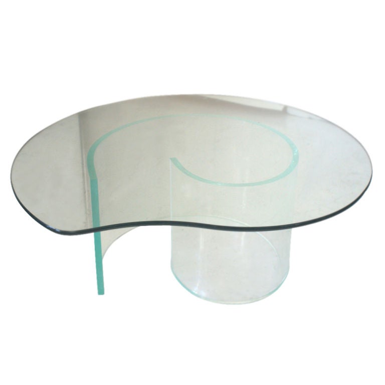 A Mid-Century Modern coffee table reminiscent of the designs of Vladimir Kagan.  An acrylic snail base with a kidney shaped glass top.