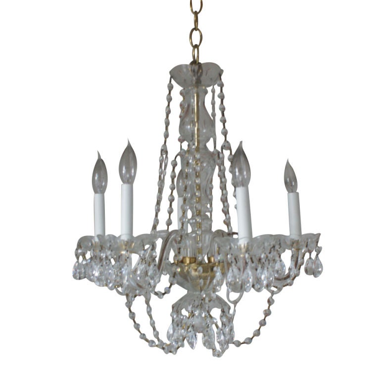 A custom made petite five light chandelier in the French style.  Brass arms with crystal drops and swags.